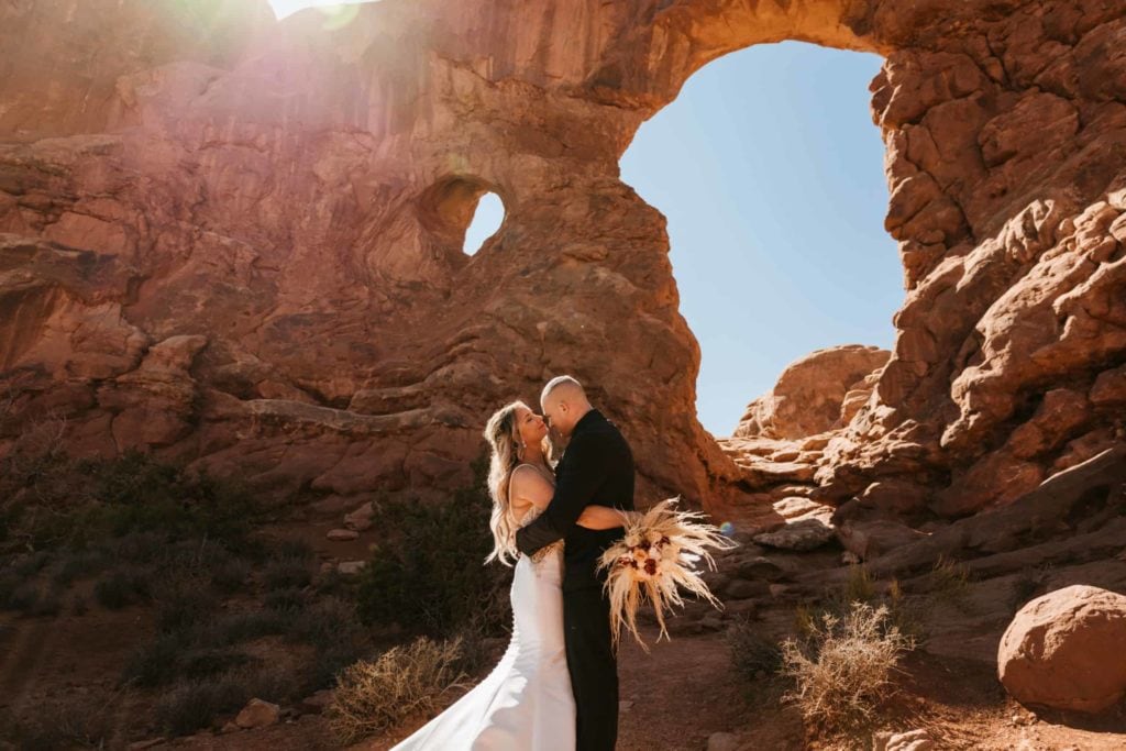 A couple holds each other close on their wedding day in Arches.