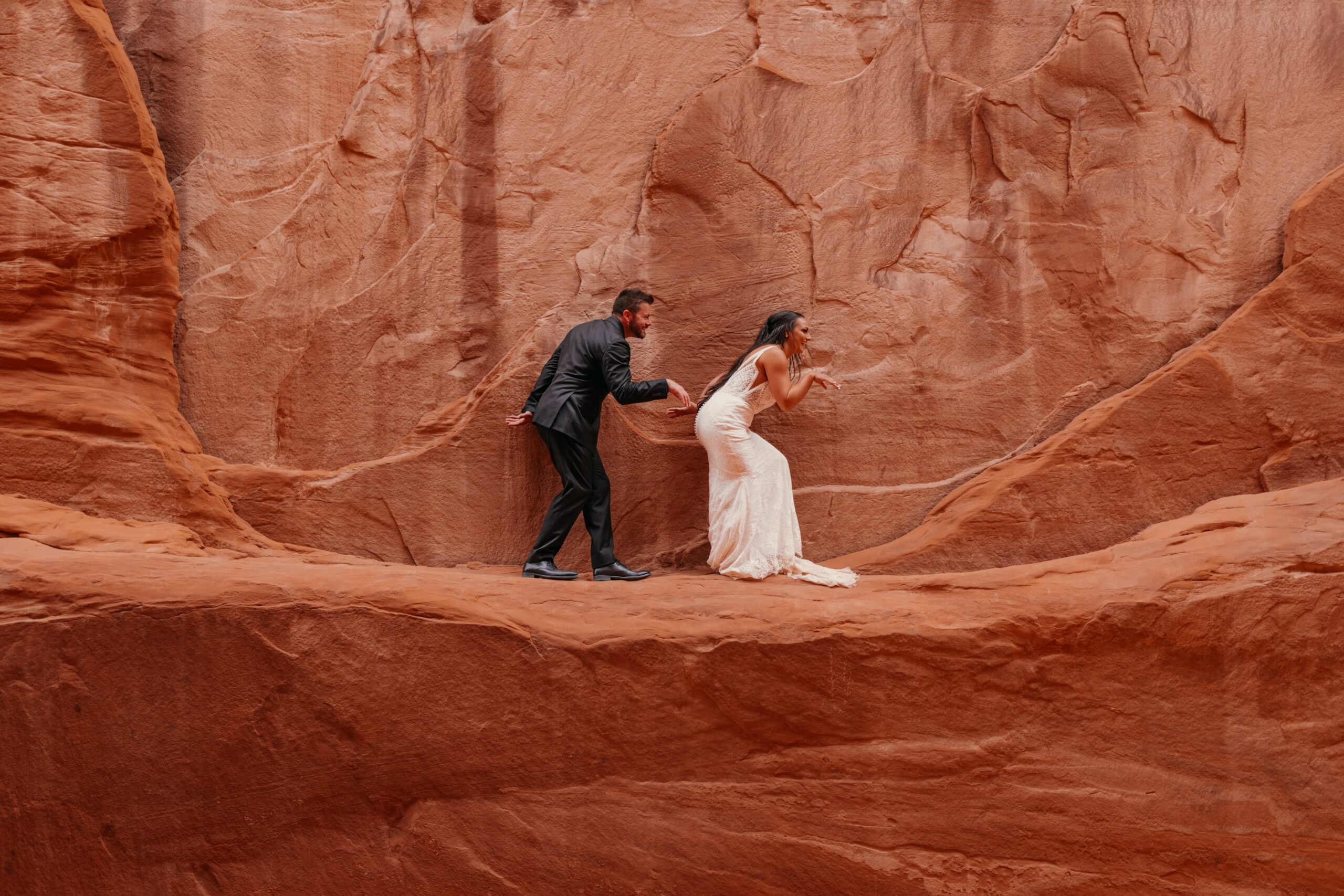 A couple pretends to be dinosaurs for a funny photo at Sand Dune Arch.