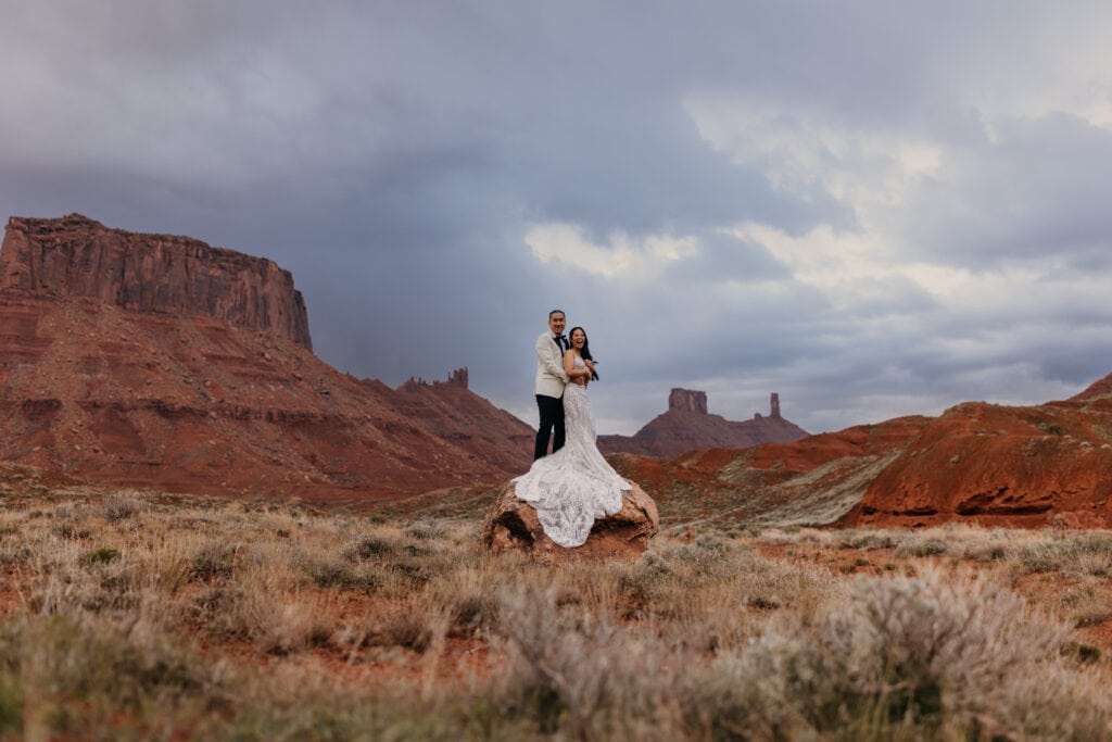 A bride and groom hold each other while near Moab.