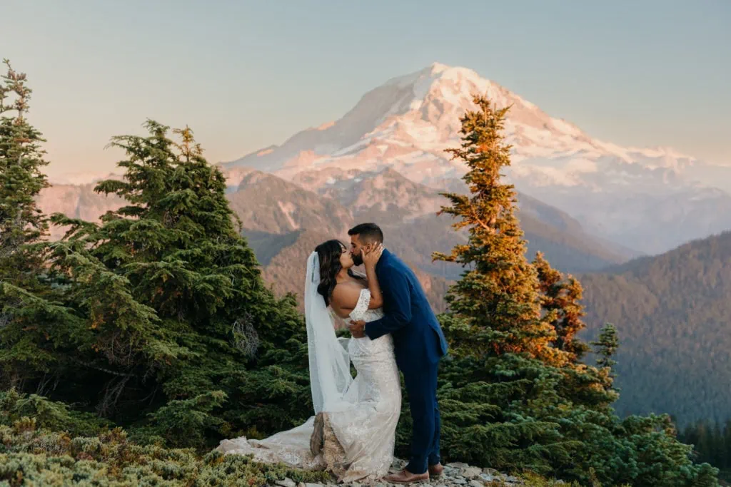 A bride grabs her groom for a kiss on their wedding day in Mt Rainier National Park at sunset.