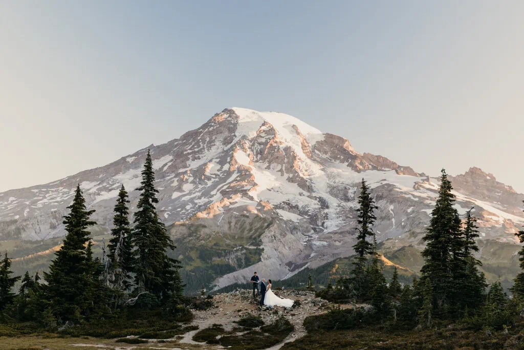 A couple shares their wedding vows with each other at an overlook of Mt Rainier at Sunrise