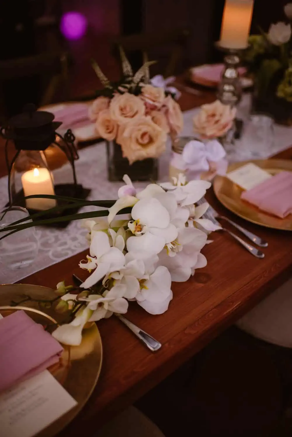 A table layout with flowers, dinner plates and other items for a wedding dinner.