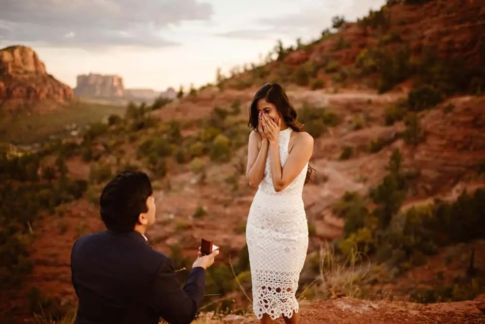 A women covers her face as she gets proposed to.