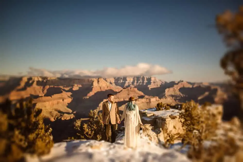 A couple looks out at the sun on a snowy day in the Grand Canyon.