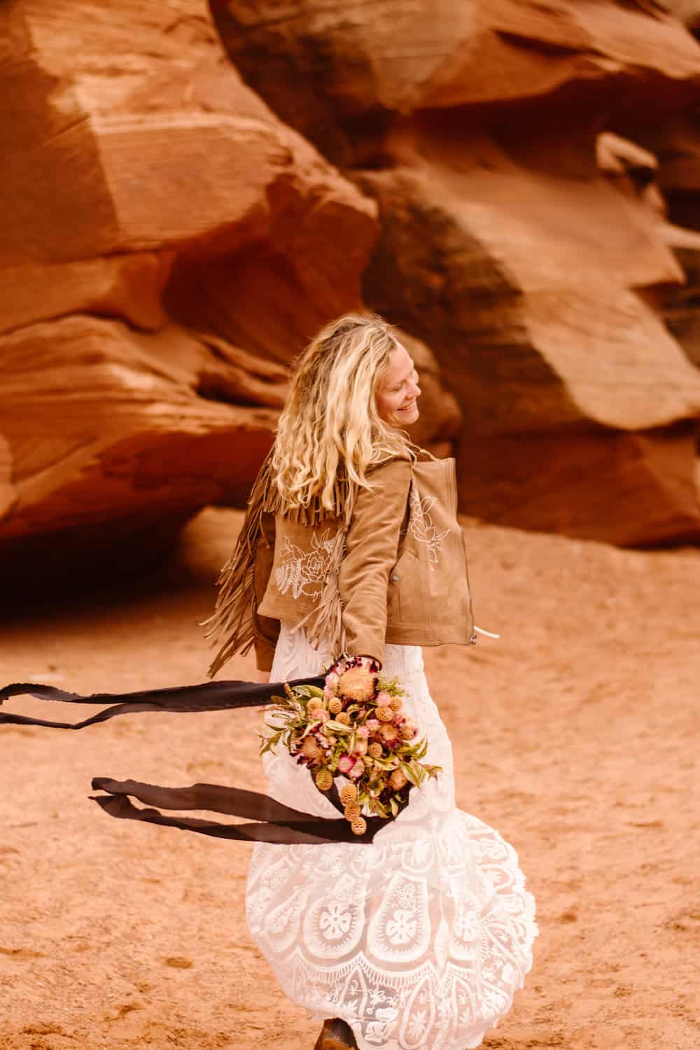 A bride spins around holding her flowers in the slot canyon.