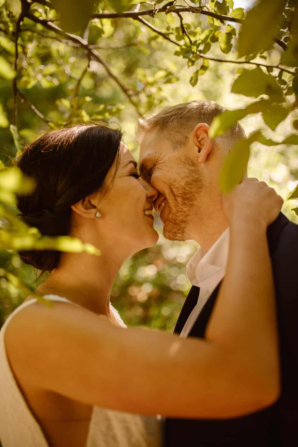 A close up of the couple sharing a kiss near the apple trees. 