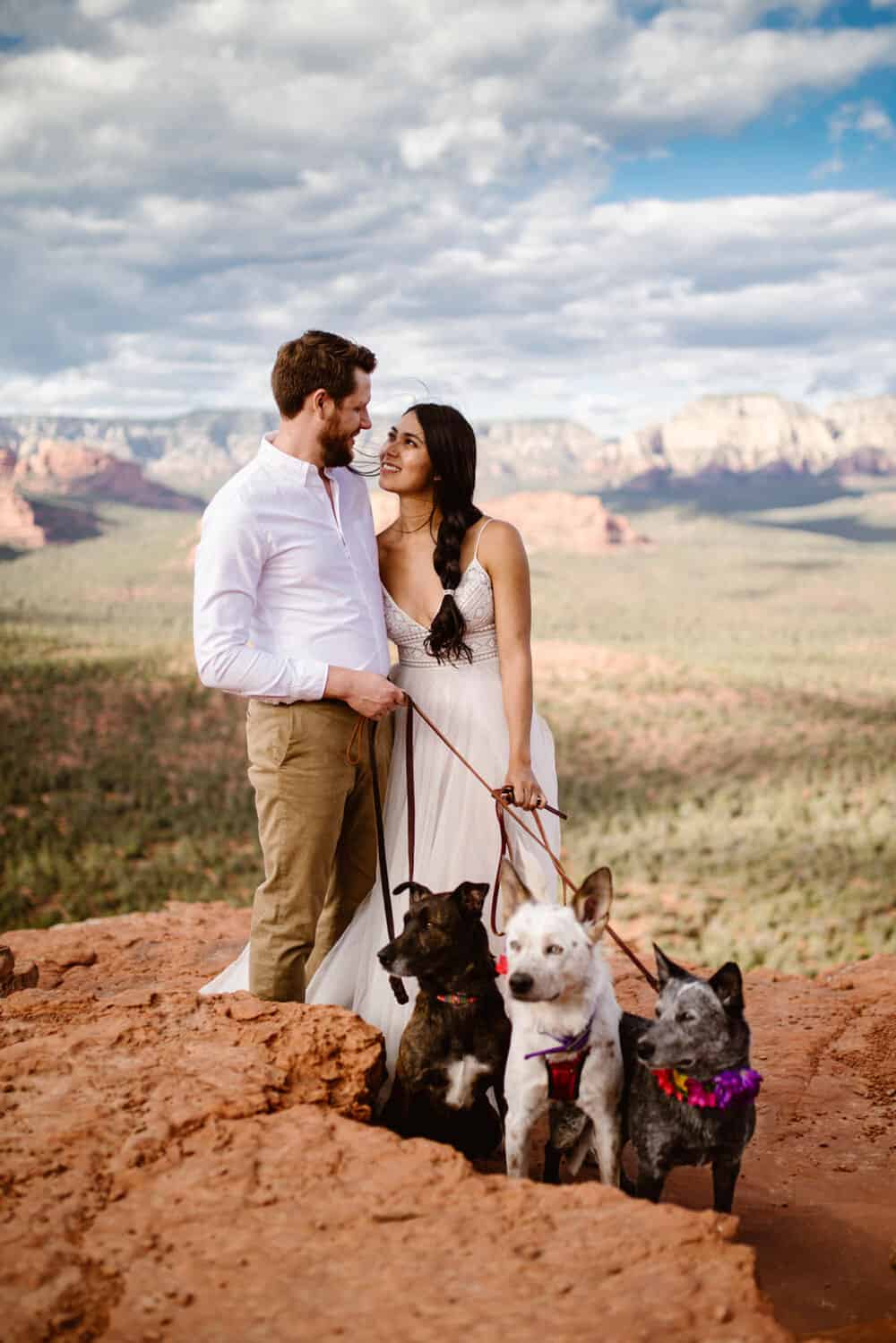 A couple looks at each other while their three dogs check out the views.