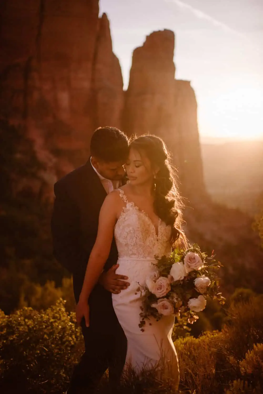 A romantic moment of a couple at sunset on Cathedral Rock as the bride holds her flowers. 