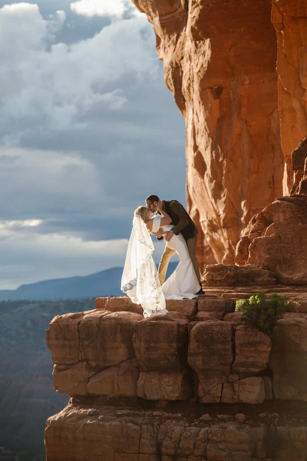 A wedding couple shares a dip kiss on a moody day at Cathedral Rock.