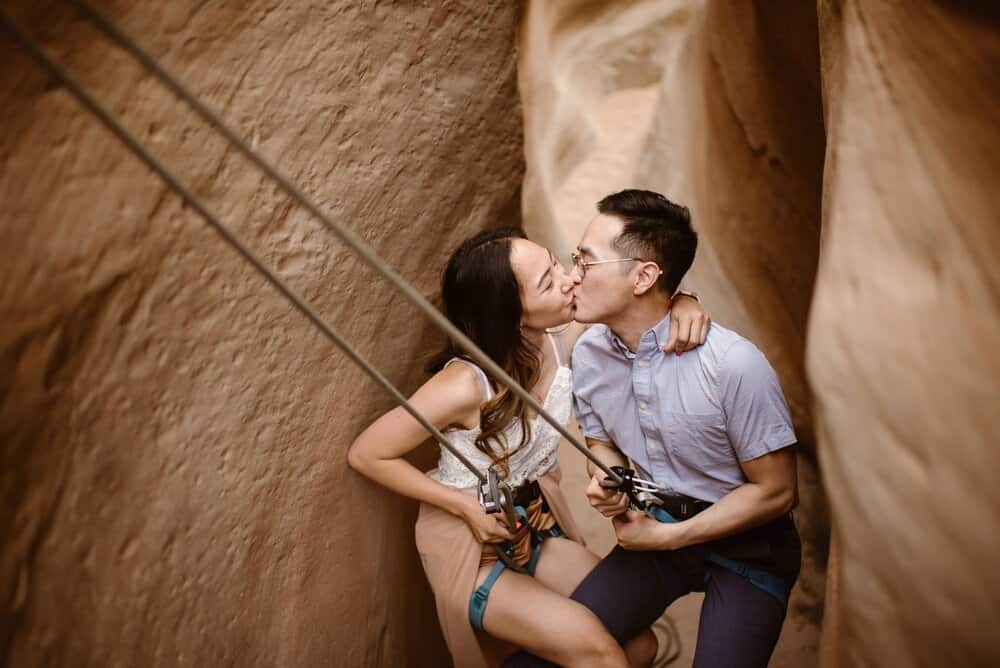 A couple shares a kiss as the repel into a slot canyon. 