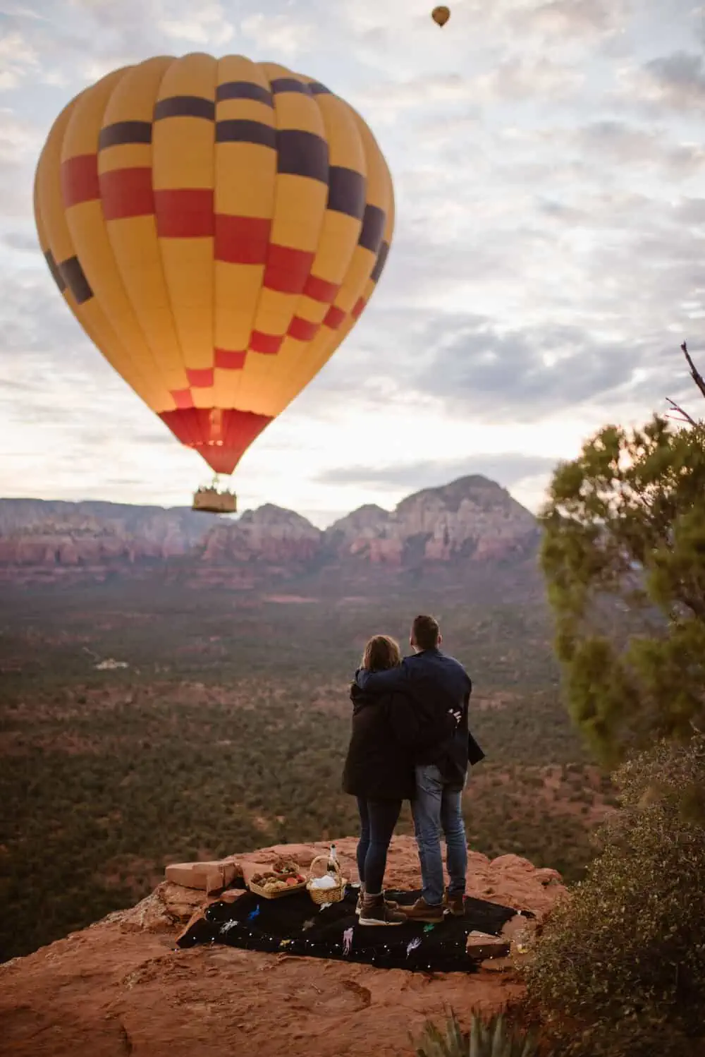 A couple watches the hot air balloons at sunrise during their proposal session.