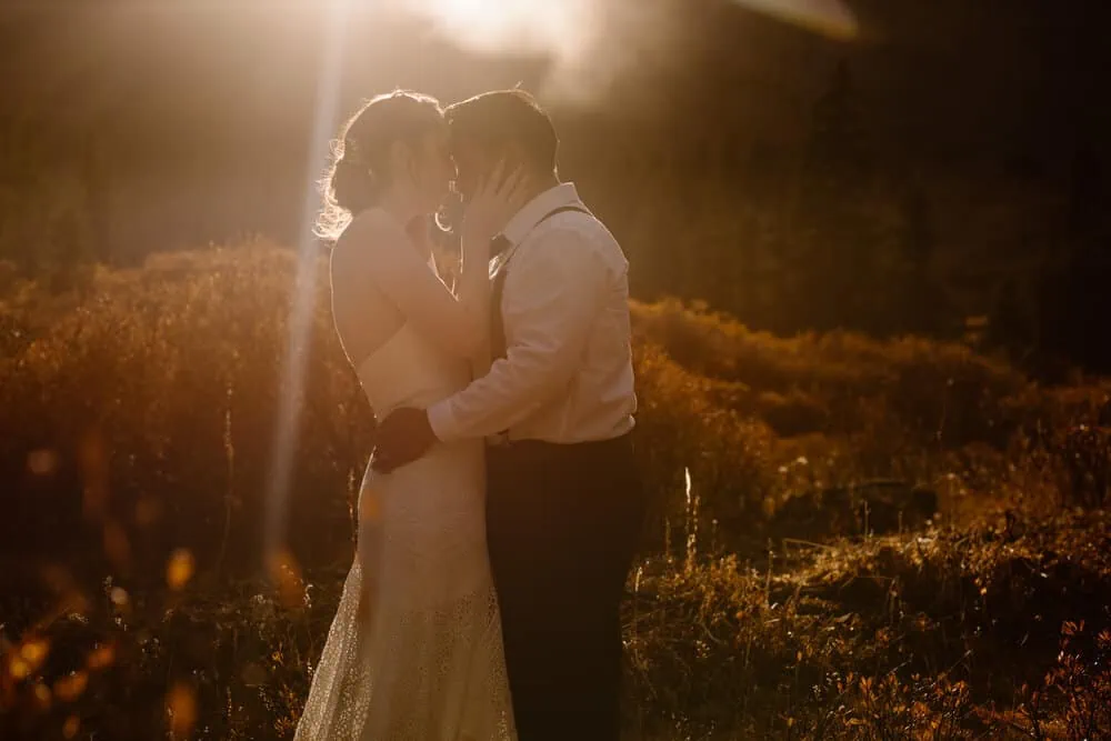 A bride and groom sharing a kiss at sunset.