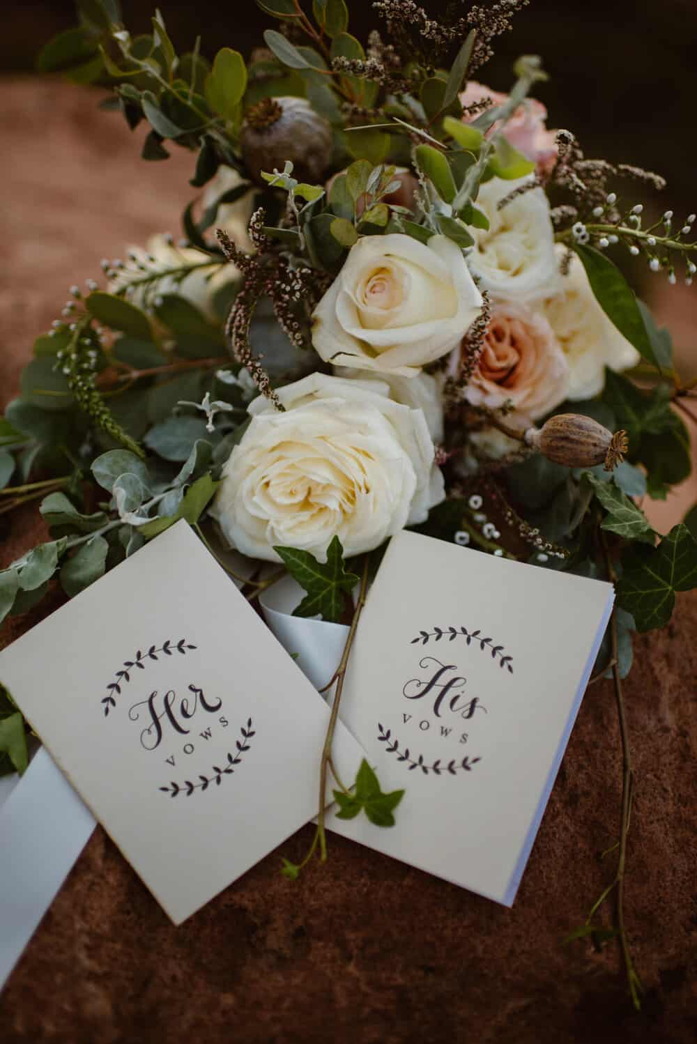 A floral bouquet and the bride and grooms vow books placed together for a styled image.
