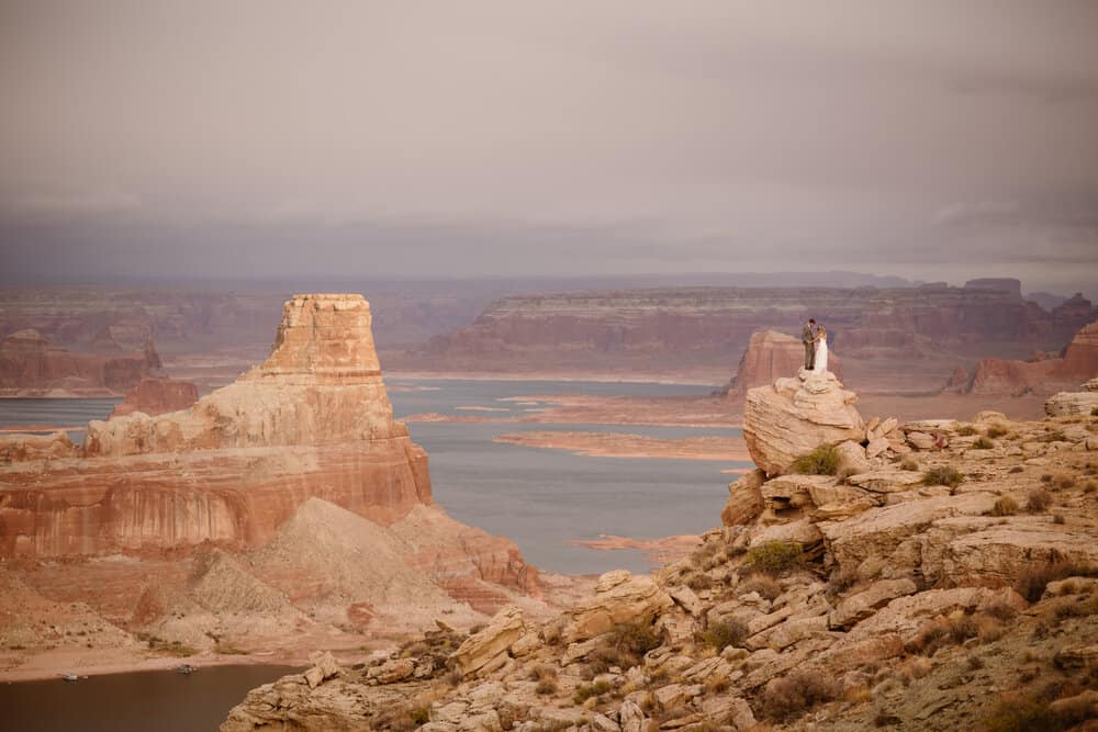 A couple stands together overlooking lake powell.