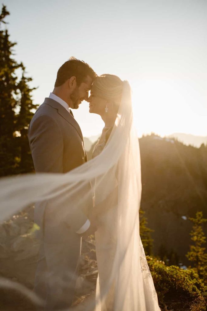 a backlit image of a bride and her veil blowing in the wind at sunset.