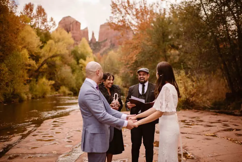 A man and woman perform the couples elopement ceremony by a river.