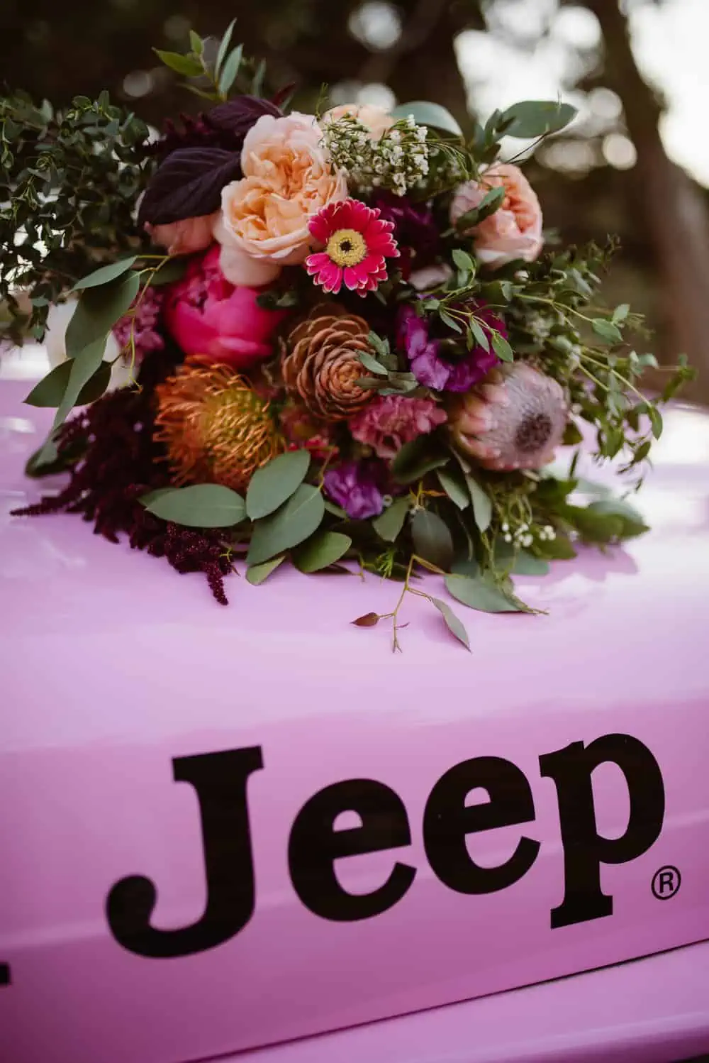 Flowers lay on top of the hood of the jeep. 