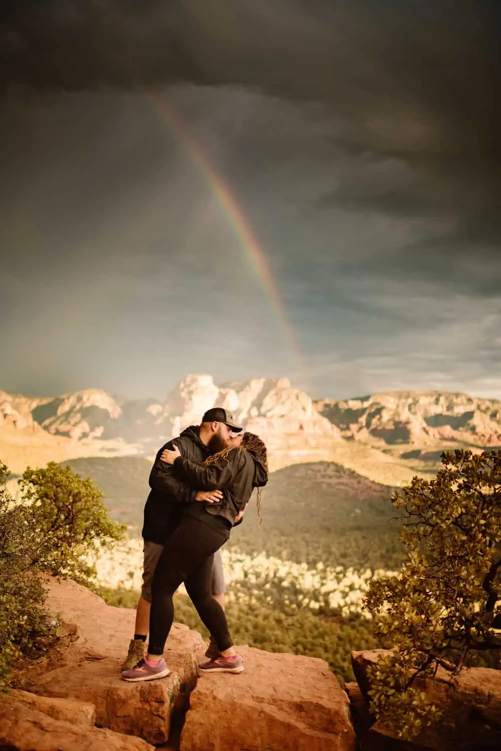 A couple shares a kiss as a rainbow appears right after becoming engaged.