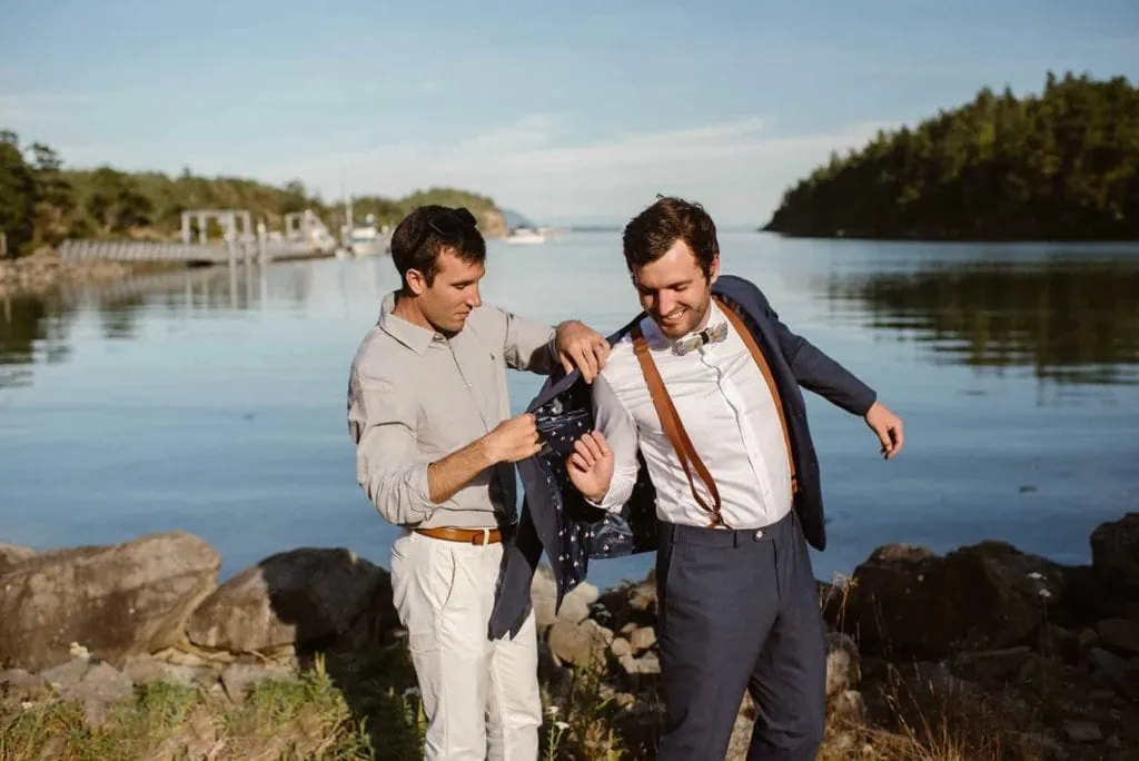 The groom puts his suit on by the bay.