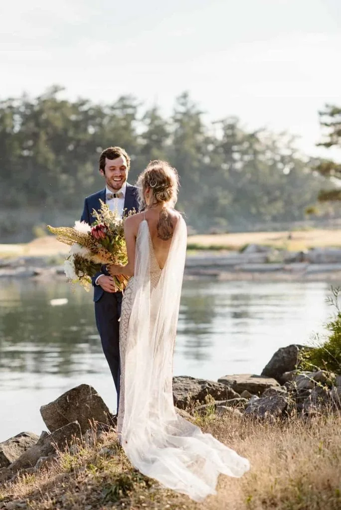 A bride and groom share their first look near the ocean