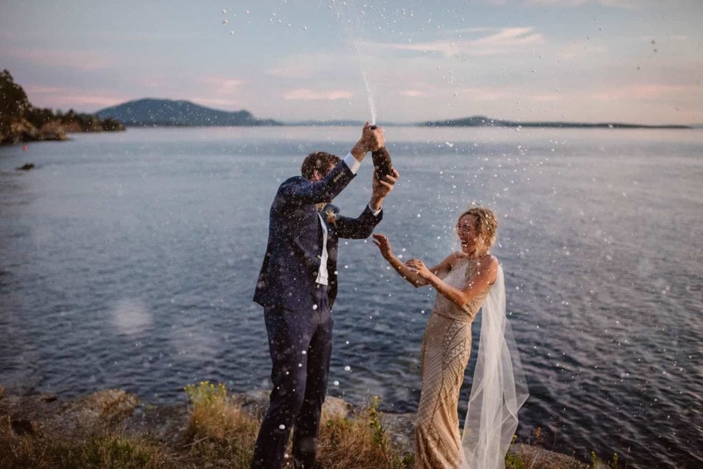 A groom sprays a bottle of champagne in celebration on Sucia Island.