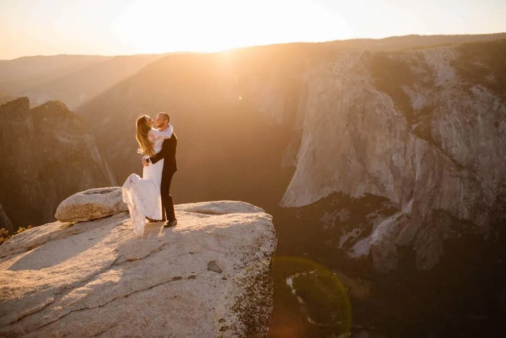 A groom picks up his bride in the sunset light at Taft Point. 