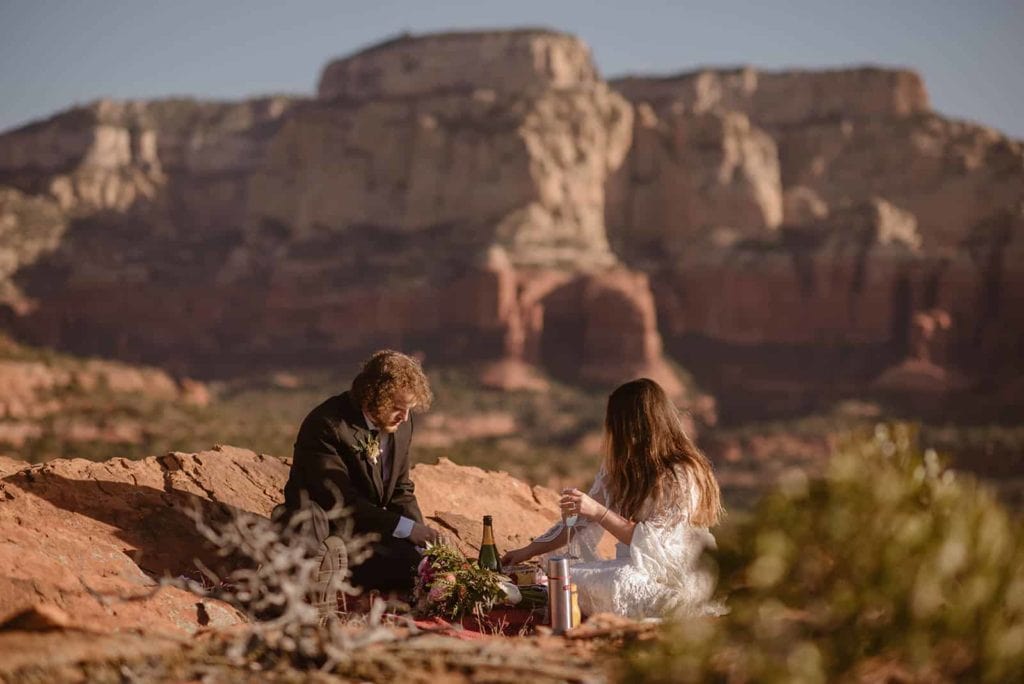 A bride and groom share a picnic in Sedona after sharing a sunrise ceremony.