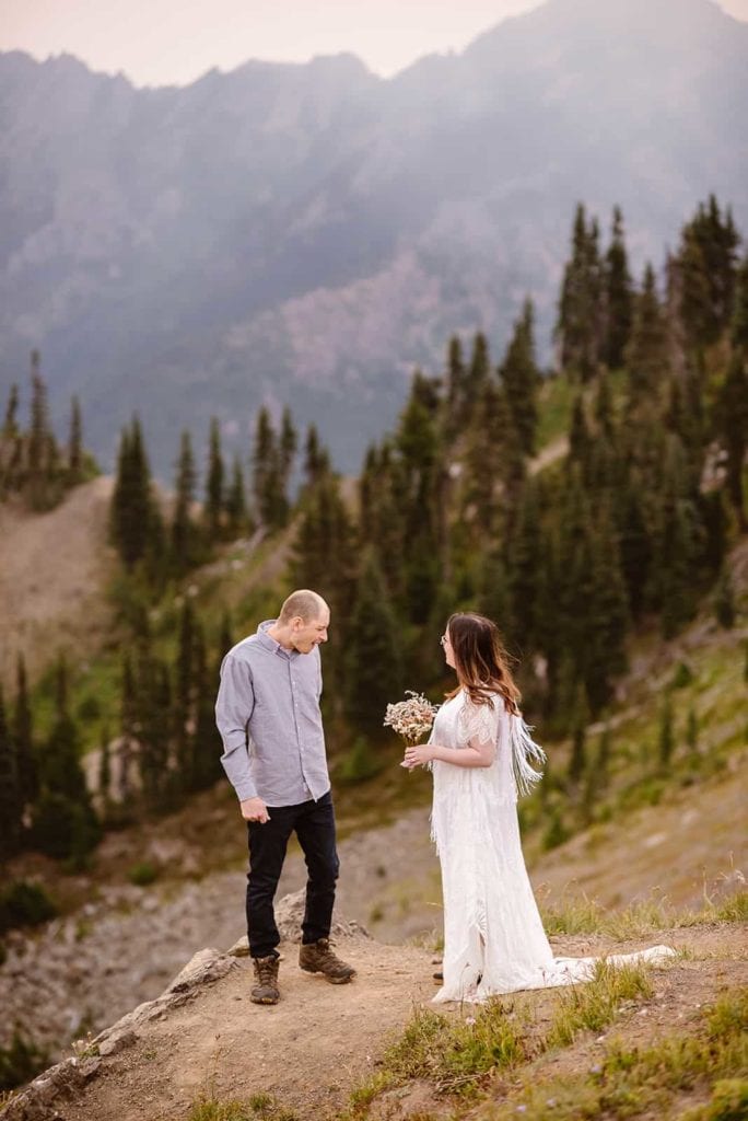 A bride and groom share a first look while out taking in the sunrise at Hurricane ridge with vast mountain views.