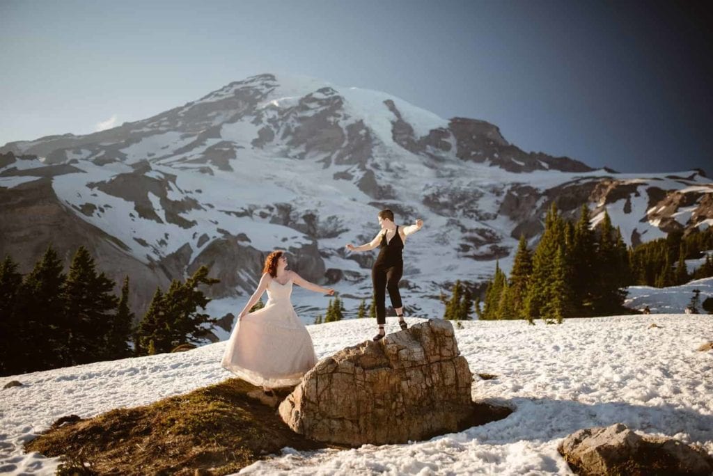 Two Brides celebrate their marriage with some dance moves on a rock at Mount Rainier national park.