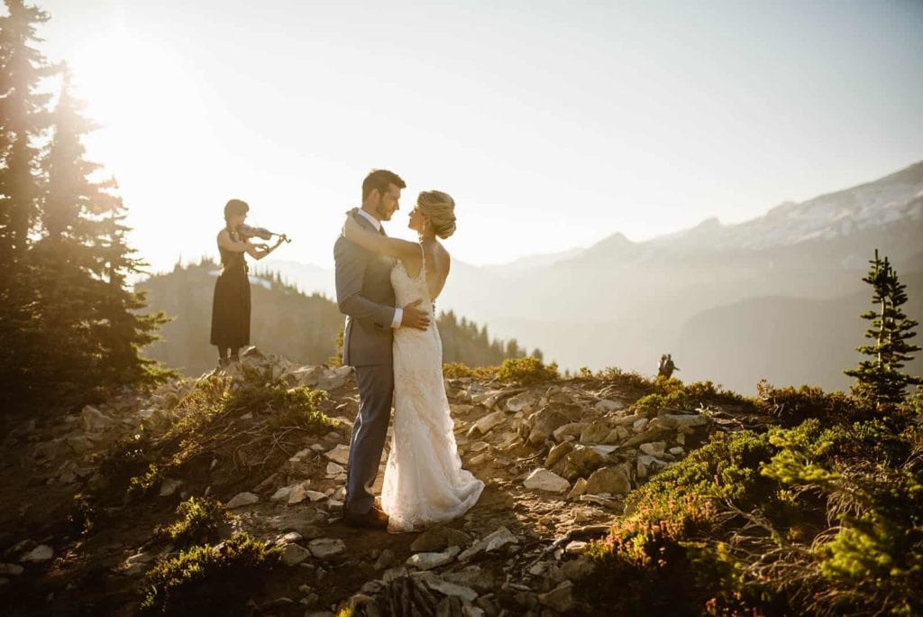 A couple shares their first dance by a live violinist in Mt Rainier National Park.