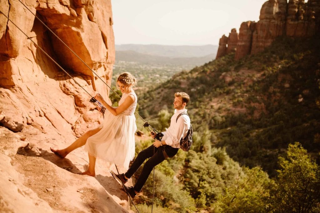 A couple rappels down the side of a rock on a sunny day in Sedona.