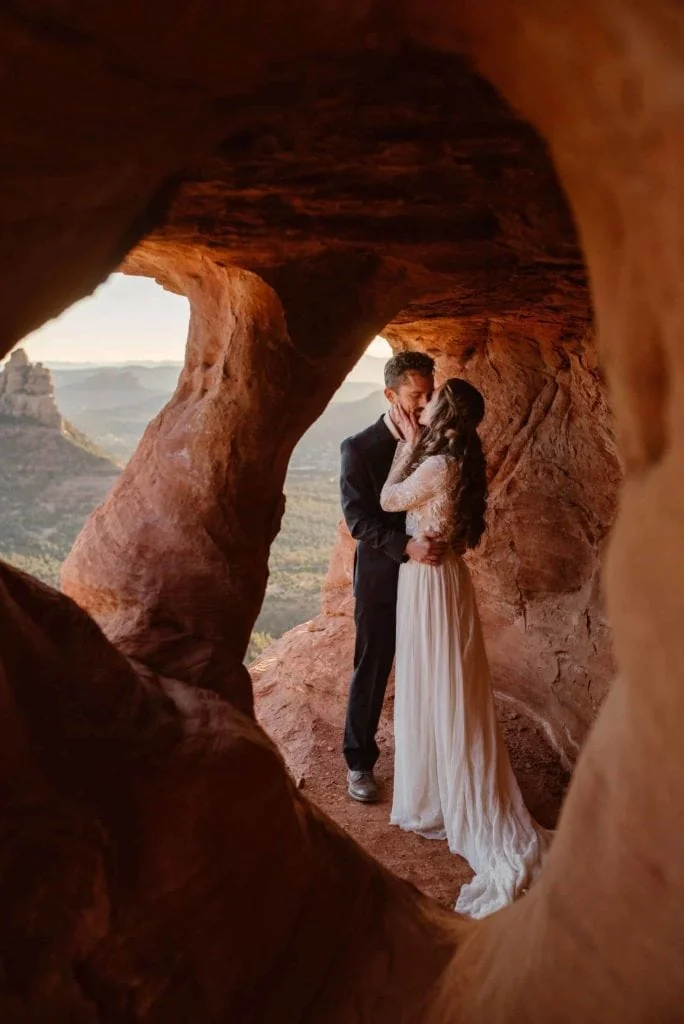 A couple kisses in a cave over looking sedona.