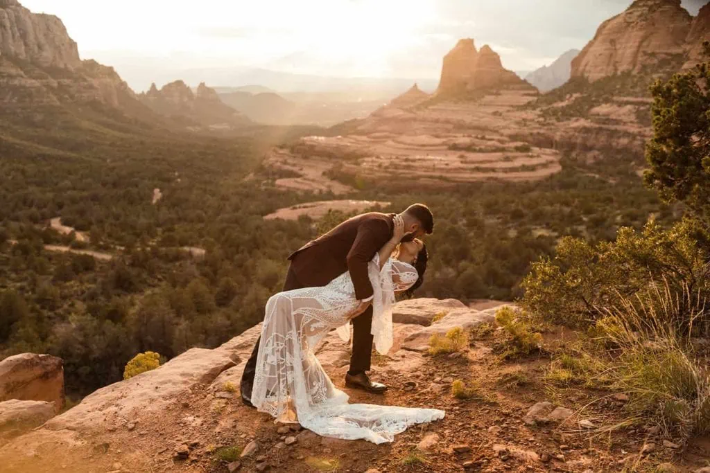 A groom dip kisses his bride in celebration of their wedding as the sunsets down over Sedona.
