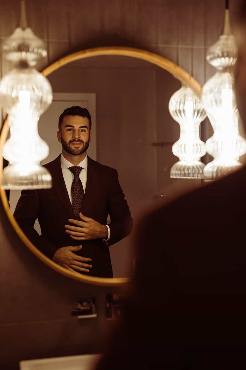 A groom gets ready in front of a mirror