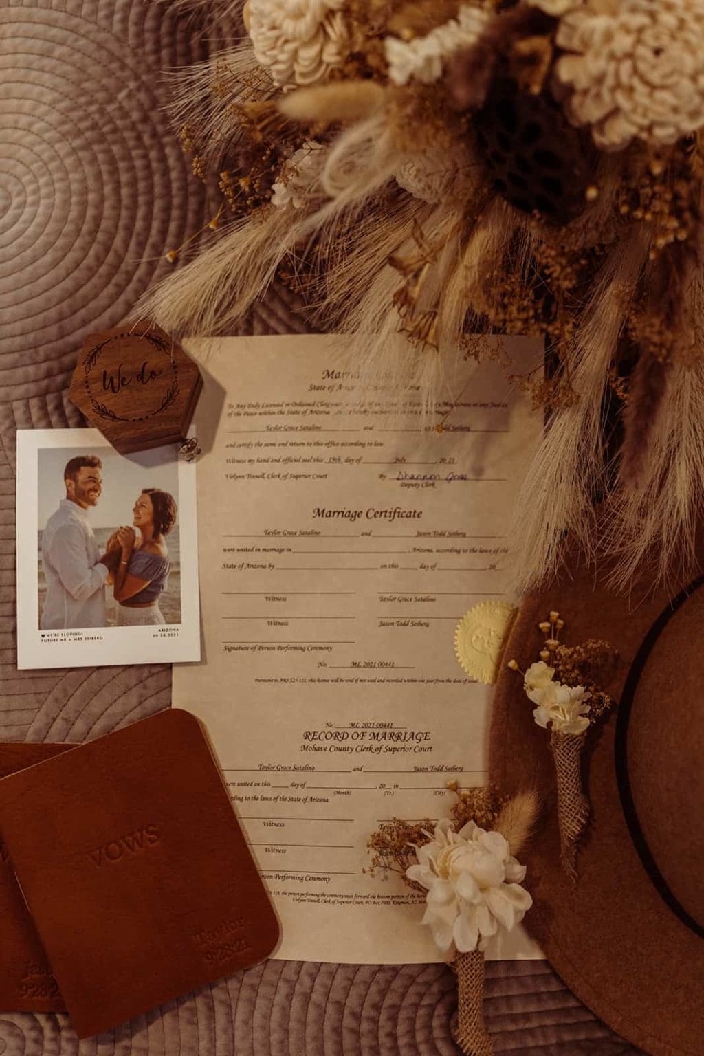 A flat lay of a marriage license with a bouquet in the corner and a photo of the soon to be married couple