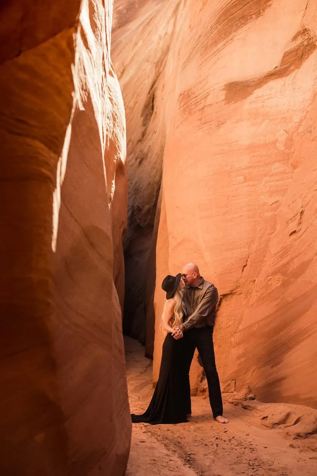 A bride and groom kiss each other in a red rock slot canyon.