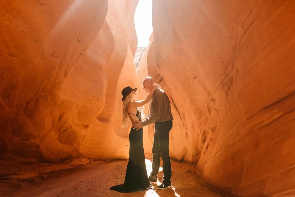 A couple hold each other in a red rock slot canyon