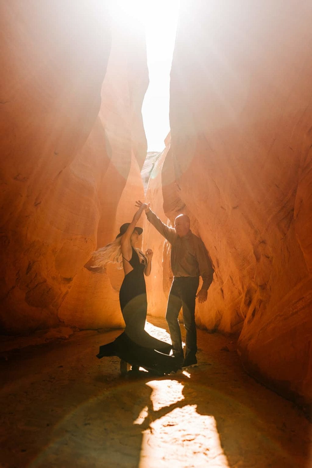 A groom spins his bride in the walls of a red rock slot canyon.