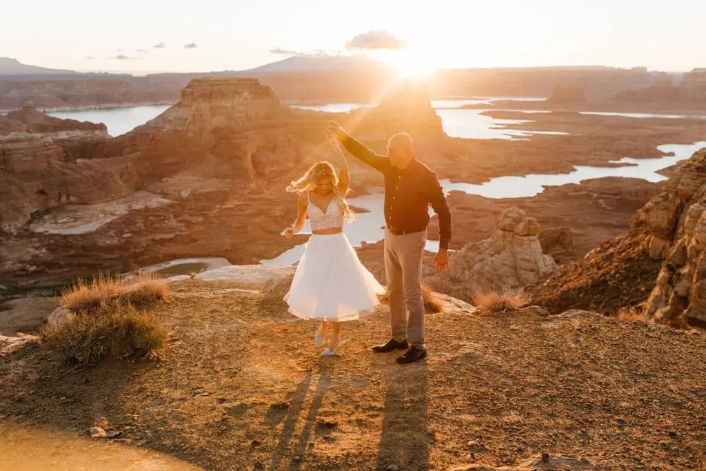 A groom spins his bride at sunrise at a vista.