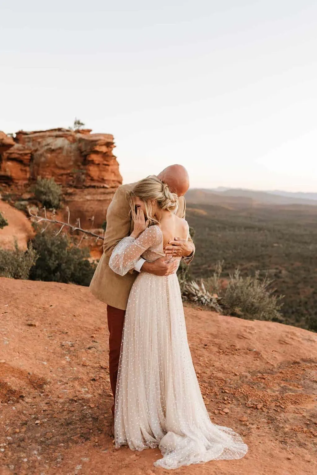 A bride wipes her tear away as her and her groom embrace each other in Sedona.