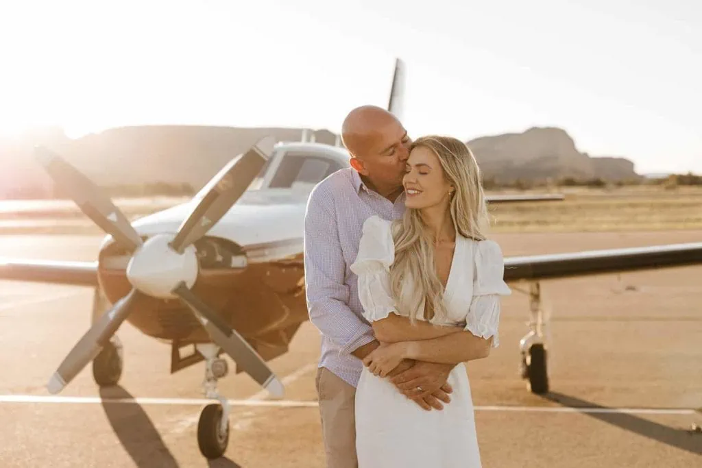 A man kisses his woman in front of an airplane at airport mesa in Sedona.