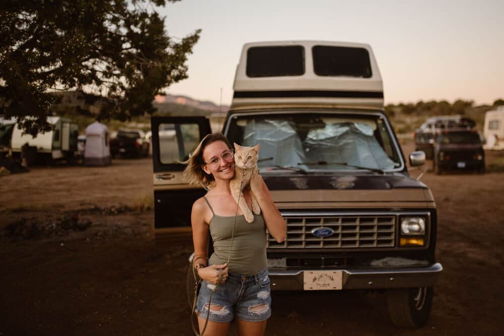 A portrait of a girl and her cat in front of her van.