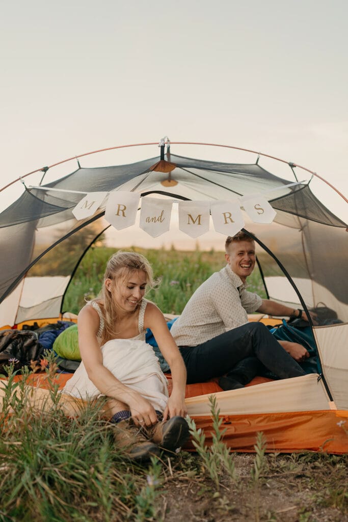 A bride and groom get settled at camp in their tent.