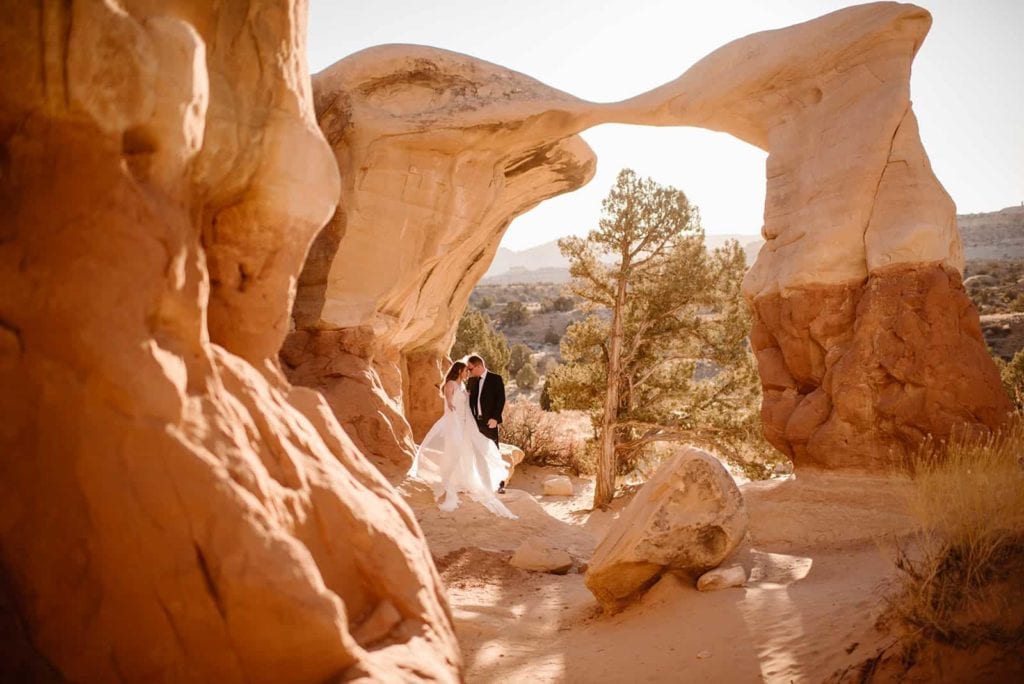 A couple stands under a famous arch in the middle of Utah.