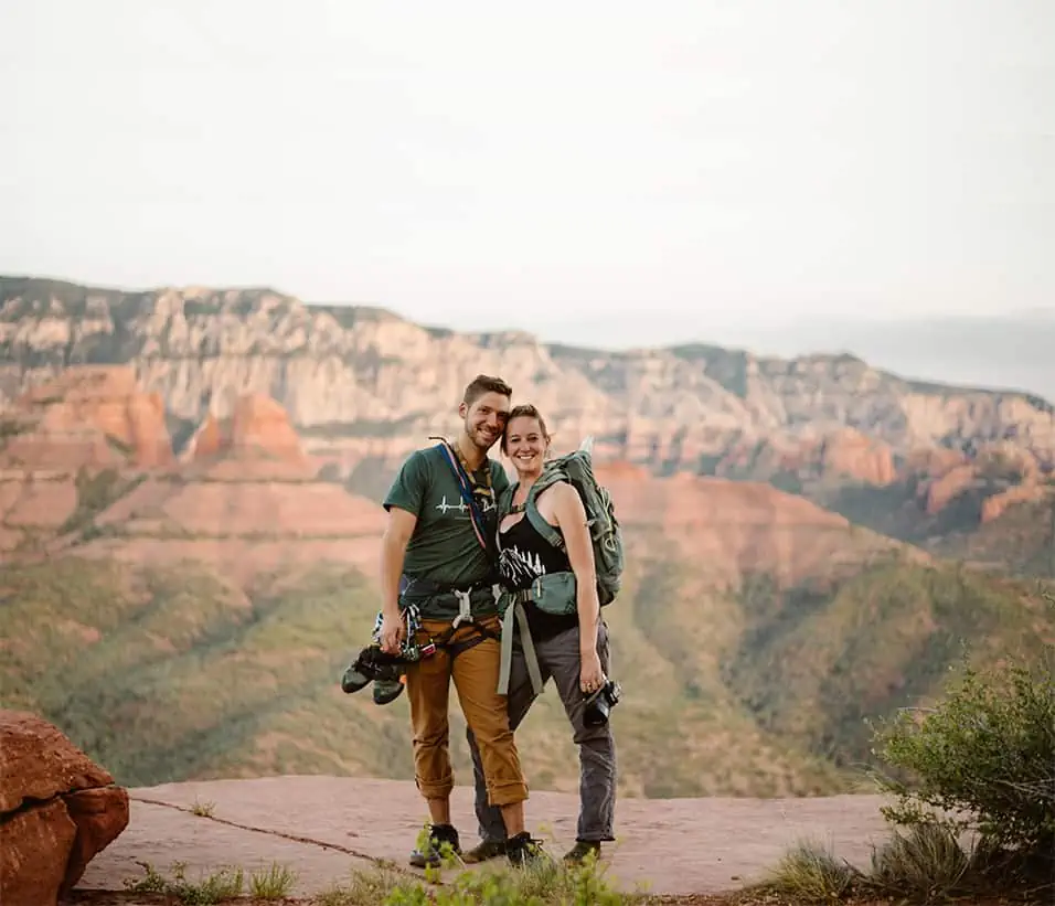 Traci and Bill stand together at sunset with all of their gear on them.
