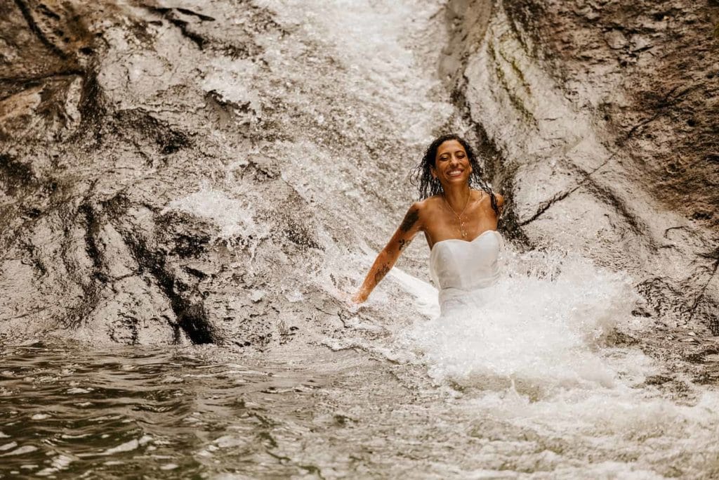 A bride as she slides down the natural waterslide created by a waterfall.
