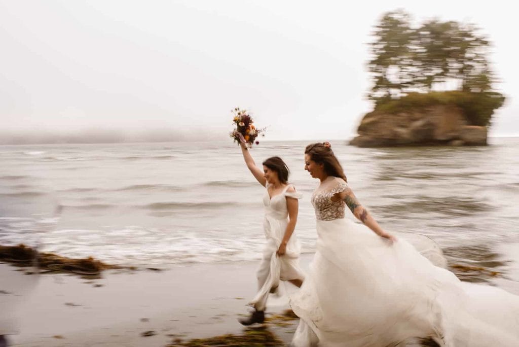 two brides running along the Oregon coast together.