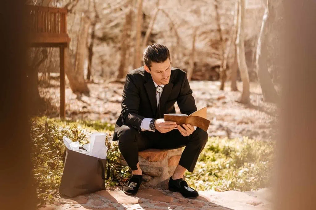 A groom sits and reads through a gift he received from his bride.