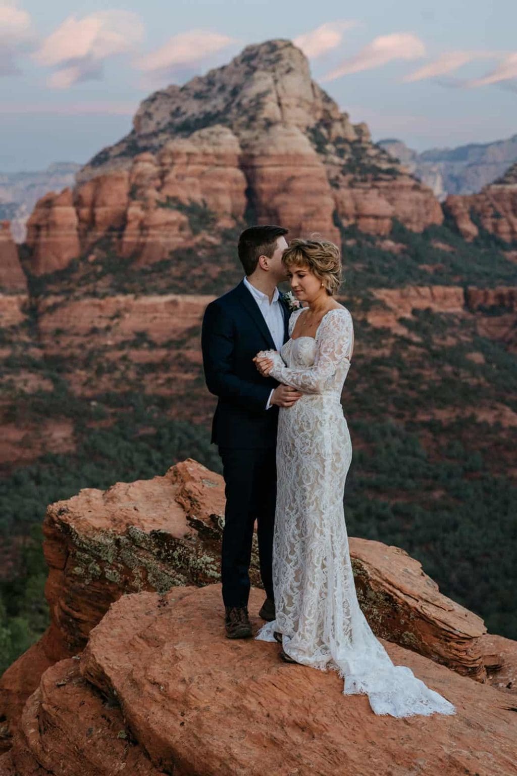 A couple stands together at sunrise in the red rocks.