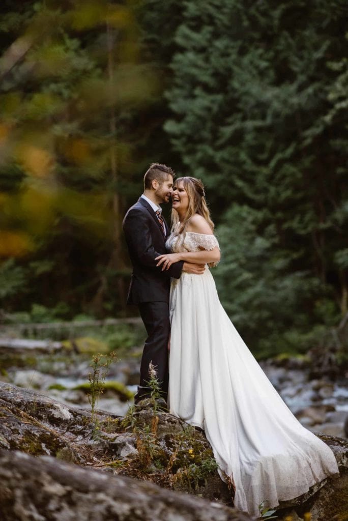 A bride laughs as her groom holds her close in the forest of Washington.